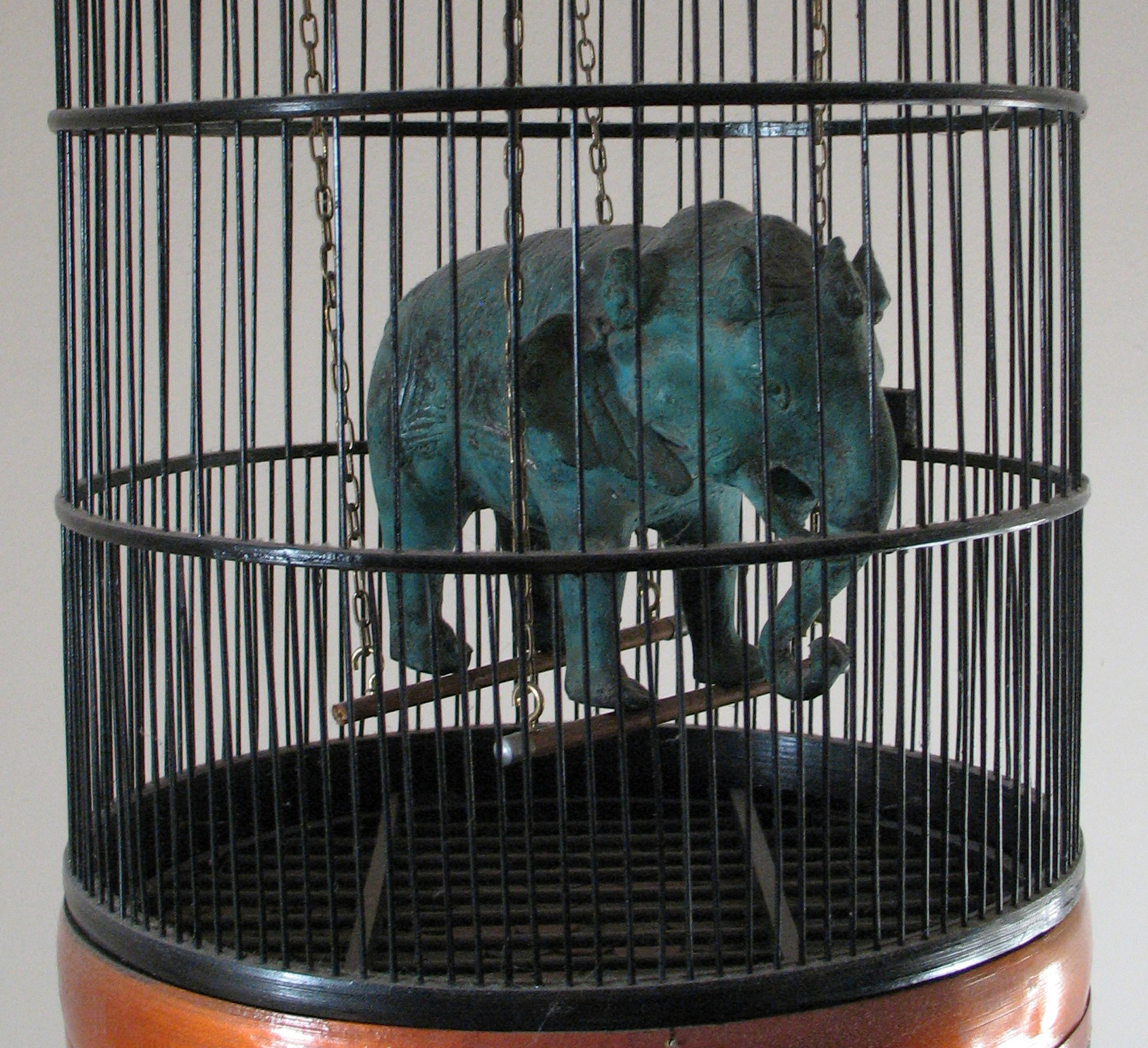 photograph of a copper elephant statuette in a bird cage 